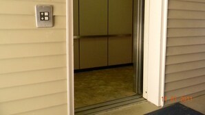 An elevator interior with a control panel and a fire safety sign. - Stay Inn & Suites (Stockbridge)
