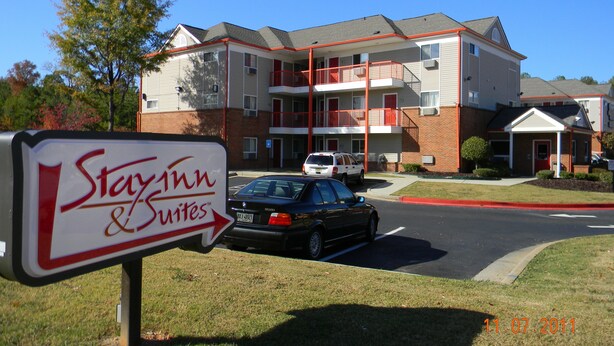 A StayInn & Suites hotel with a two-story building, a parking lot, and a signboard. - Stay Inn & Suites (Stockbridge)