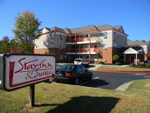 Un hotel StayInn & Suites con un edificio de dos pisos, un estacionamiento y un letrero.
