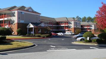 A multi-story hotel with a parking lot in front.