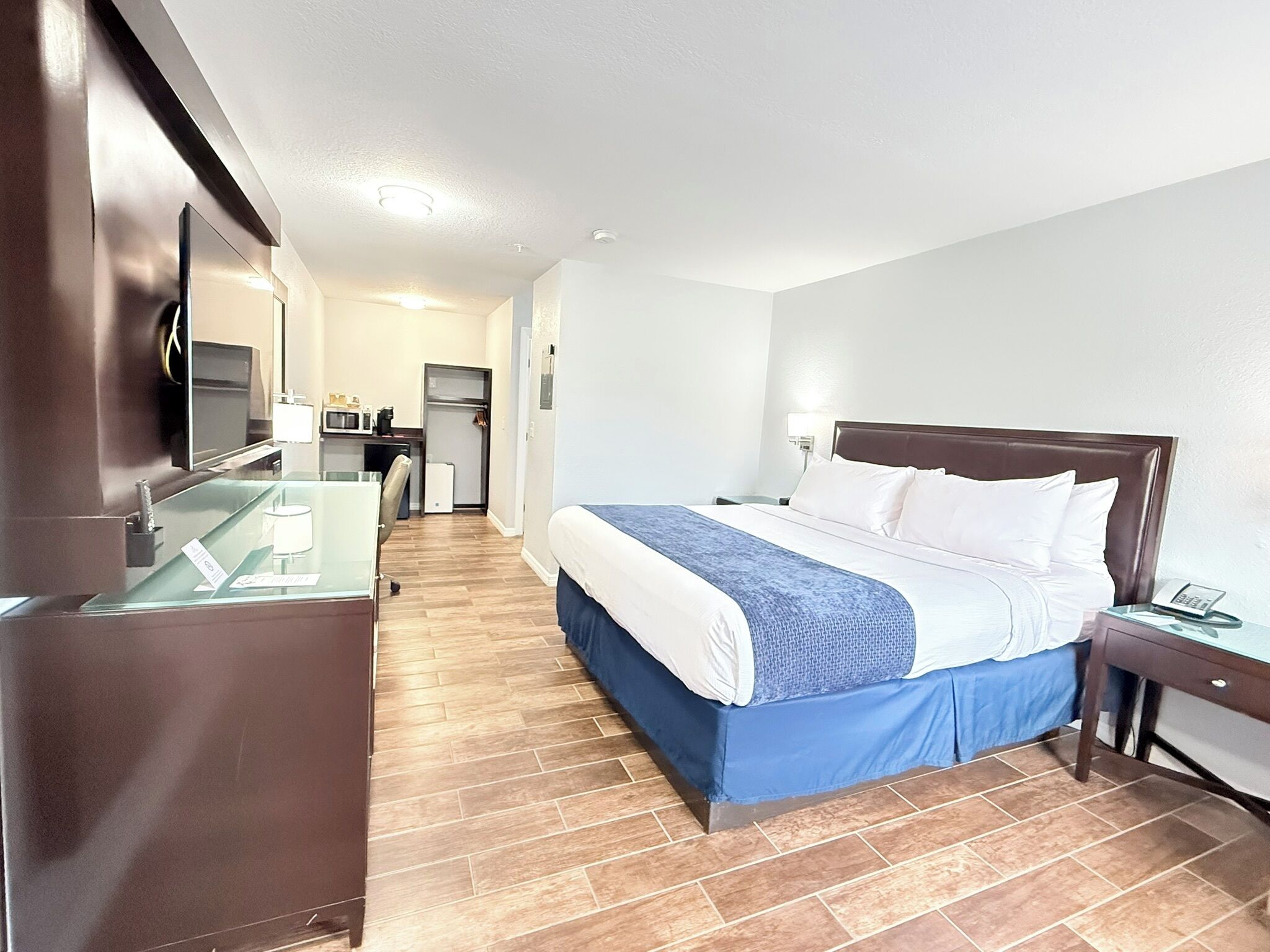 A hotel room with a bed, bedside table, and a desk with a chair.