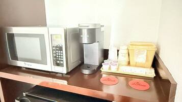 Et tekøkken med mikrobølgeovn, kaffemaskine og opbevaringsbeholdere.