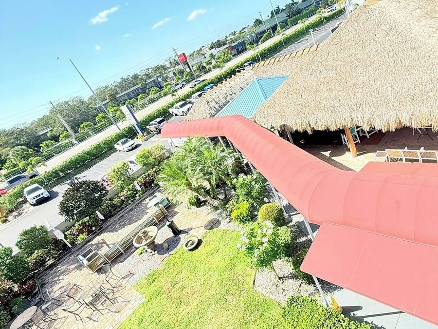 Terraço no telhado com estrutura de colmo, mobiliário para área externa e vista da região circundante, incluindo uma estrada e edifícios.