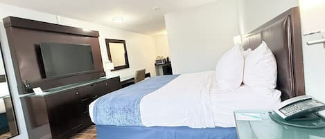 A hotel room with a bed, a TV, a desk, and a phone.