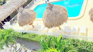 A pool area with thatched umbrellas, lounge chairs, and a clear blue pool. - Lantern Inn & Suites (Sarasota)