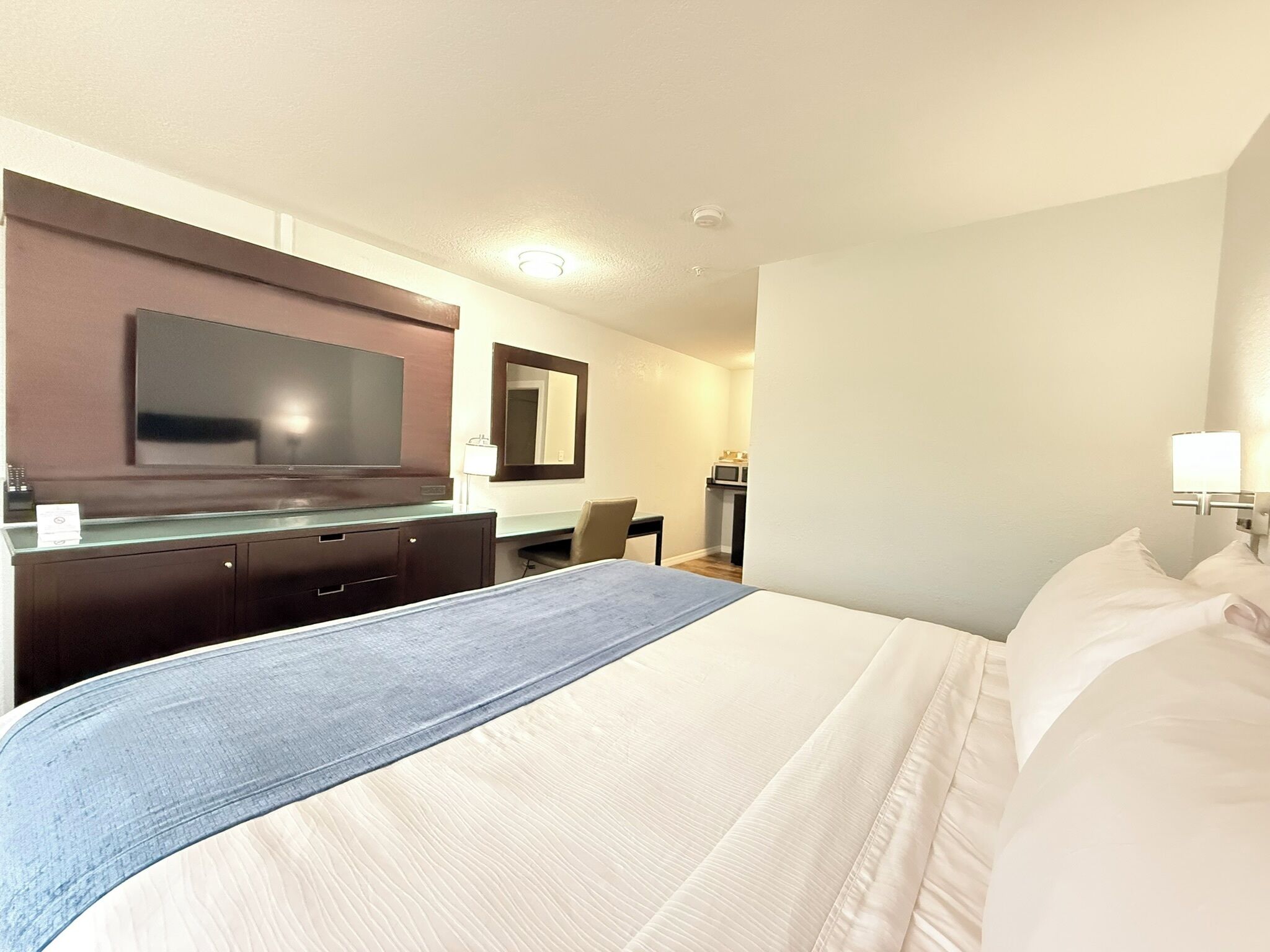 Une chambre d’hôtel comprenant un lit, un bureau, une chaise, une télévision et un miroir.