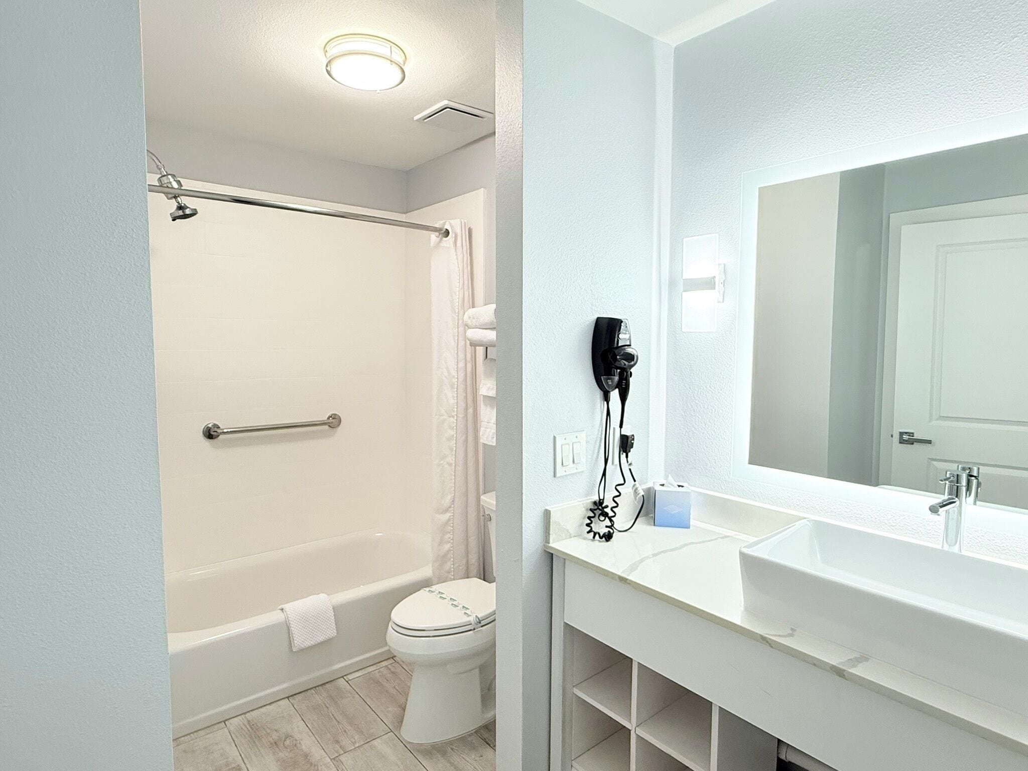 Ein Badezimmer mit Badewanne, Toilette und einem großen Spiegel über dem Waschbecken.