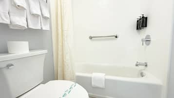 A bathroom with a toilet, a bathtub, a shower curtain, and toiletries on the wall.