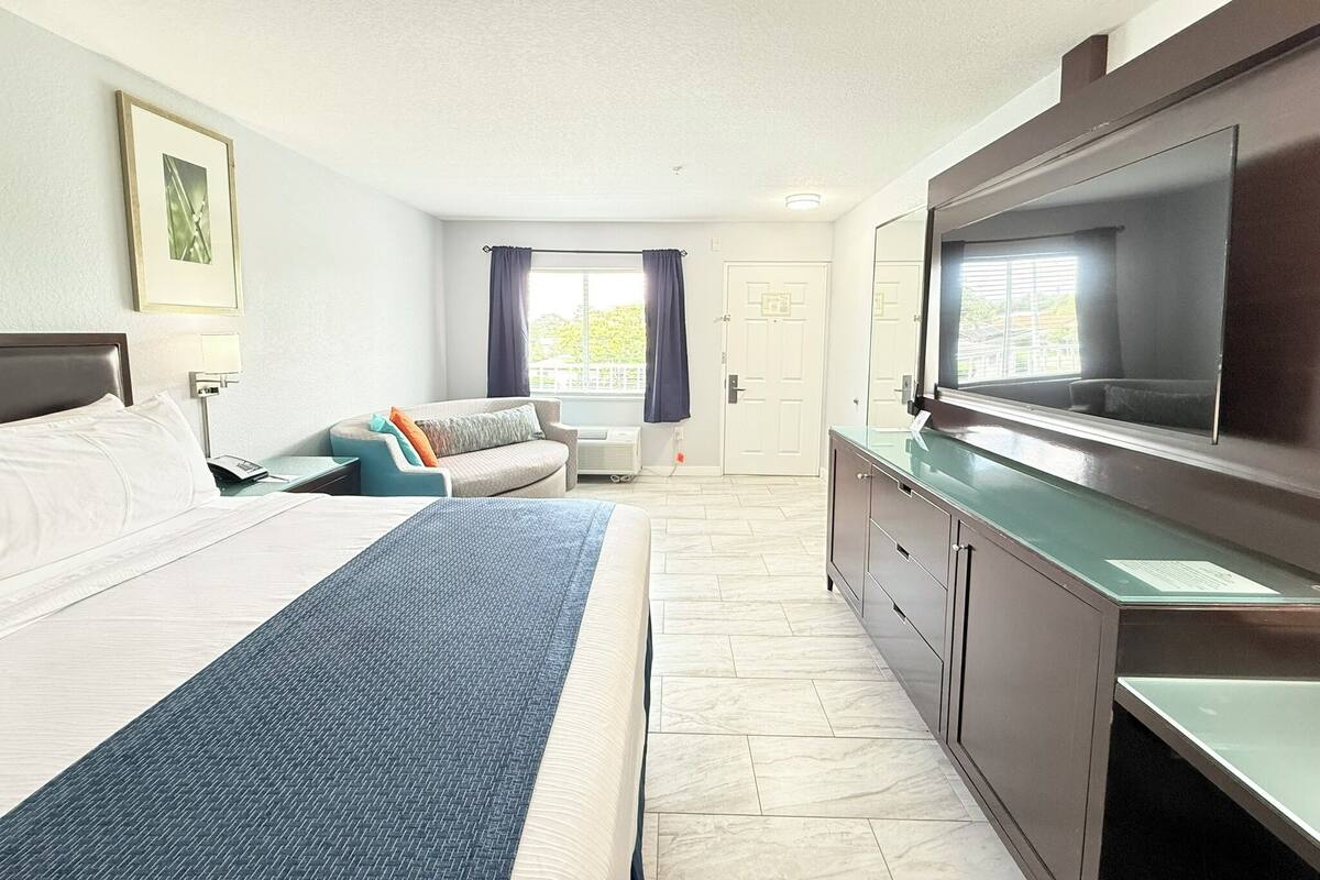 A hotel room with a bed, a sofa, a TV, and a desk.