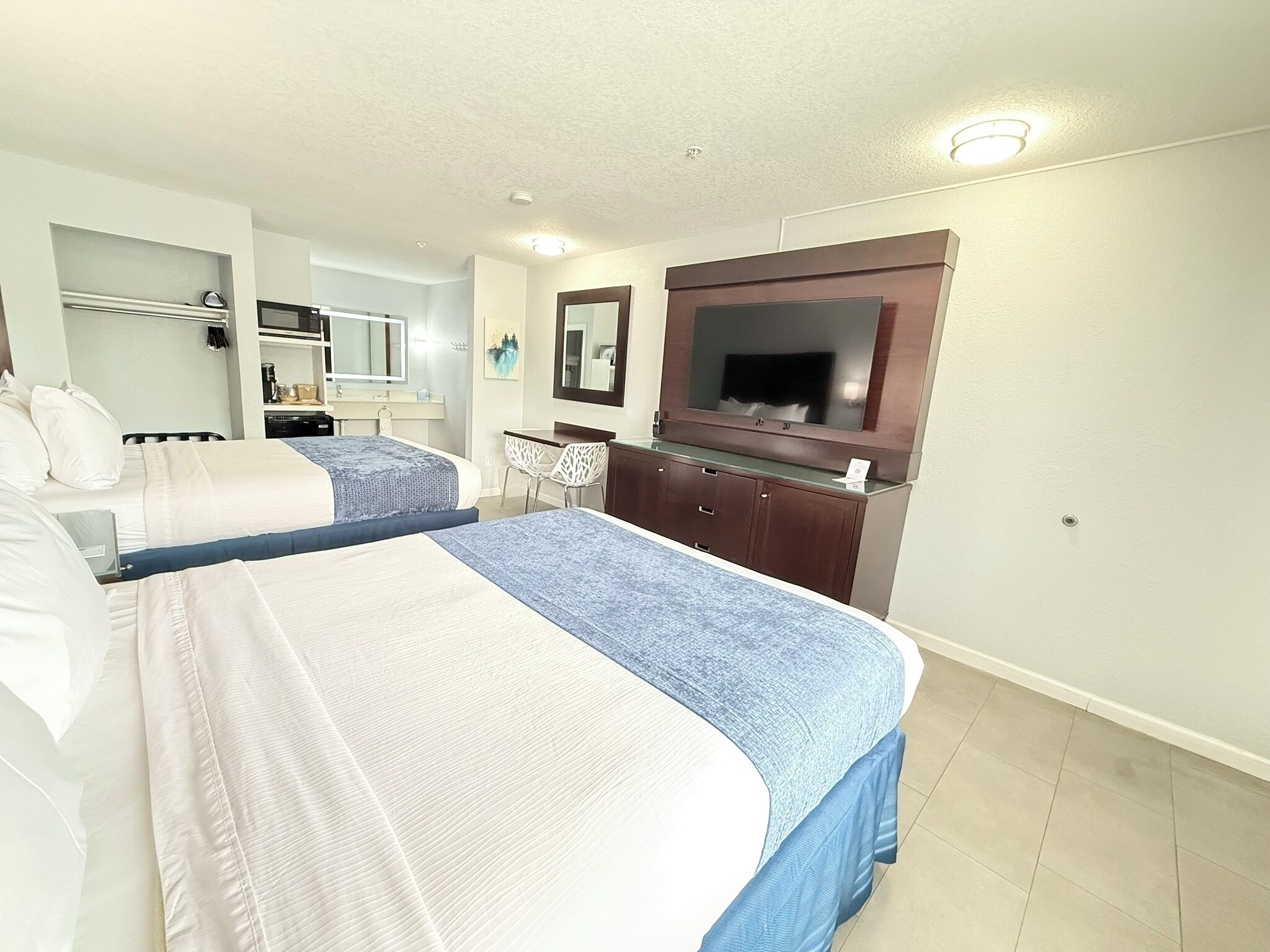 A hotel room with two beds, a TV, a desk, and a chair.