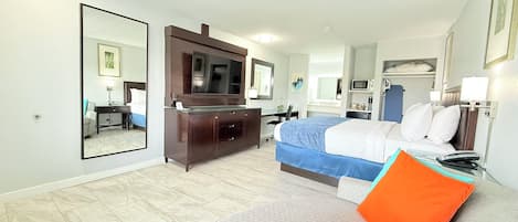 A hotel room with a bed, a desk, a dresser, a TV, and a large mirror.