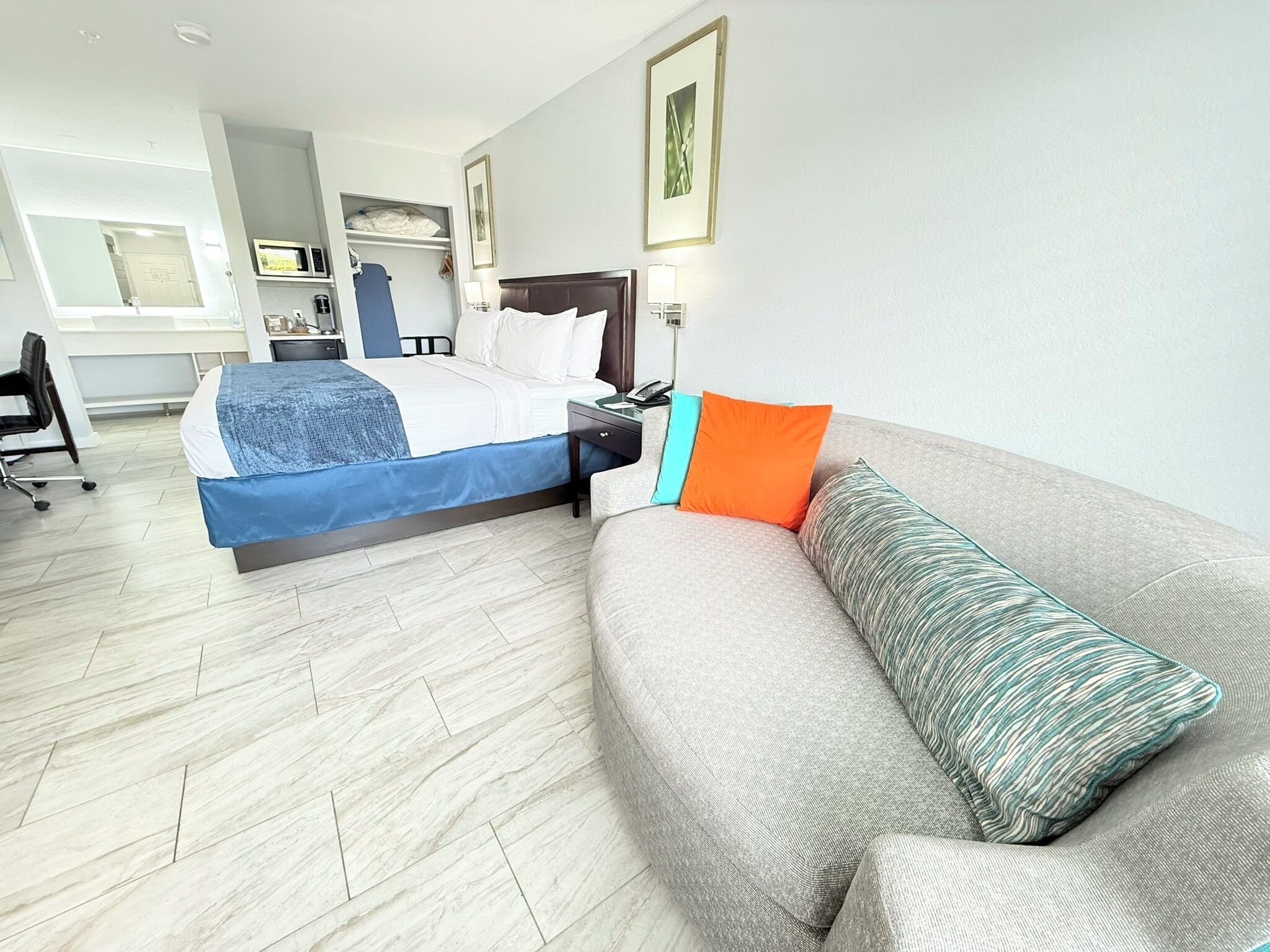 A hotel room with a bed, a sofa, a desk, and a chair.