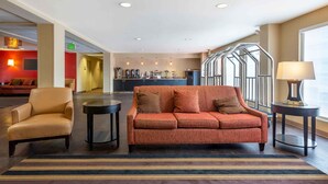 A hotel lobby with a sofa, armchair, and coffee bar. - Extended Stay America Suites Secaucus New York City Area (Secaucus)