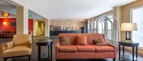 A hotel lobby with a sofa, armchair, and coffee bar.