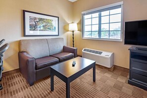 Una habitación con sofá, una mesa, una lámpara, televisor y ventana con vista.