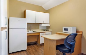 Una cocina compacta con refrigerador, microondas, pileta y muebles de madera.