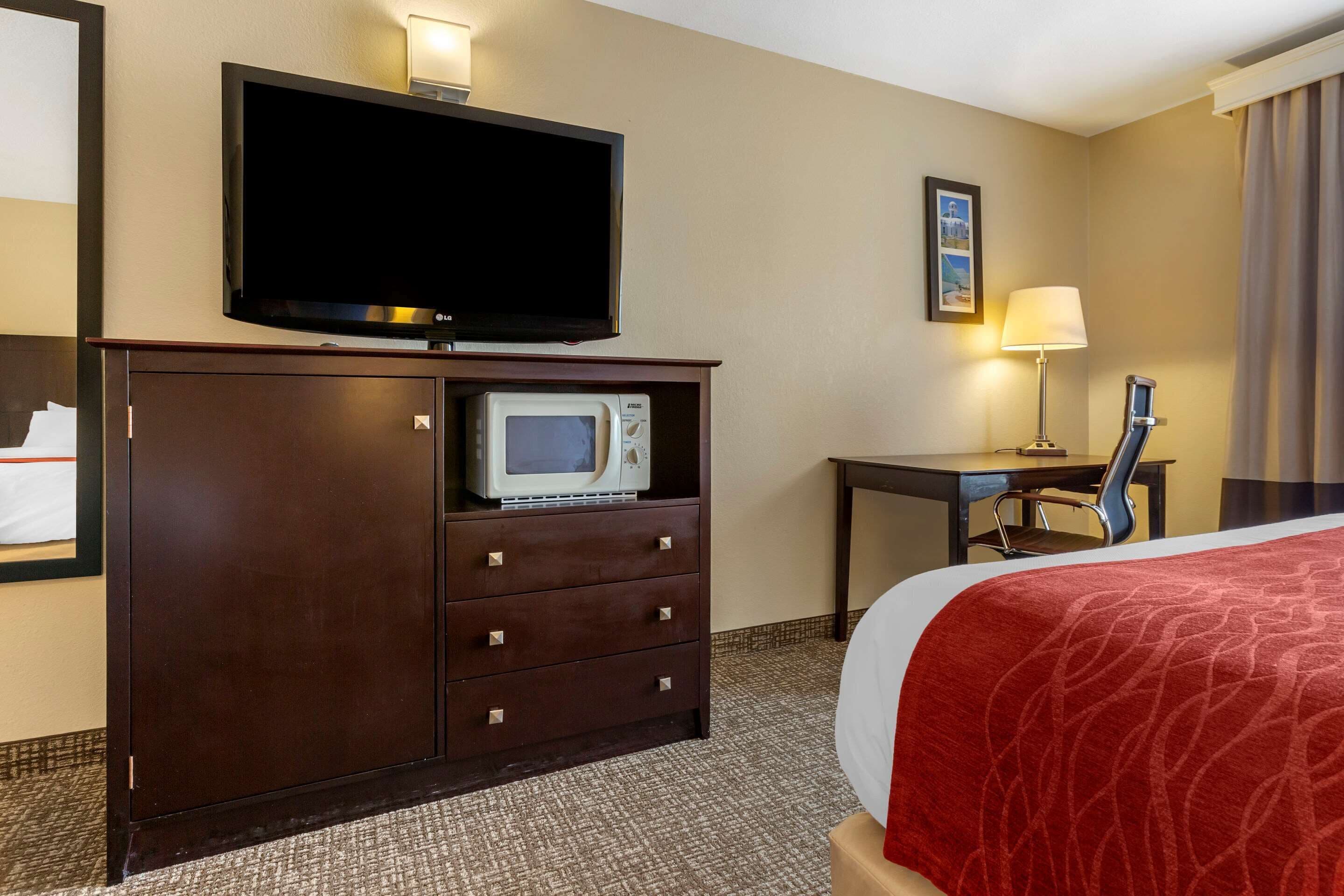 A hotel room with a bed, a TV, a microwave, a desk, and a chair.