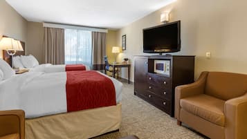 A hotel room with two beds, a TV, a desk, and a sofa.