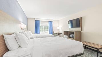 Habitación de hotel con dos camas, un escritorio, televisor y microondas.