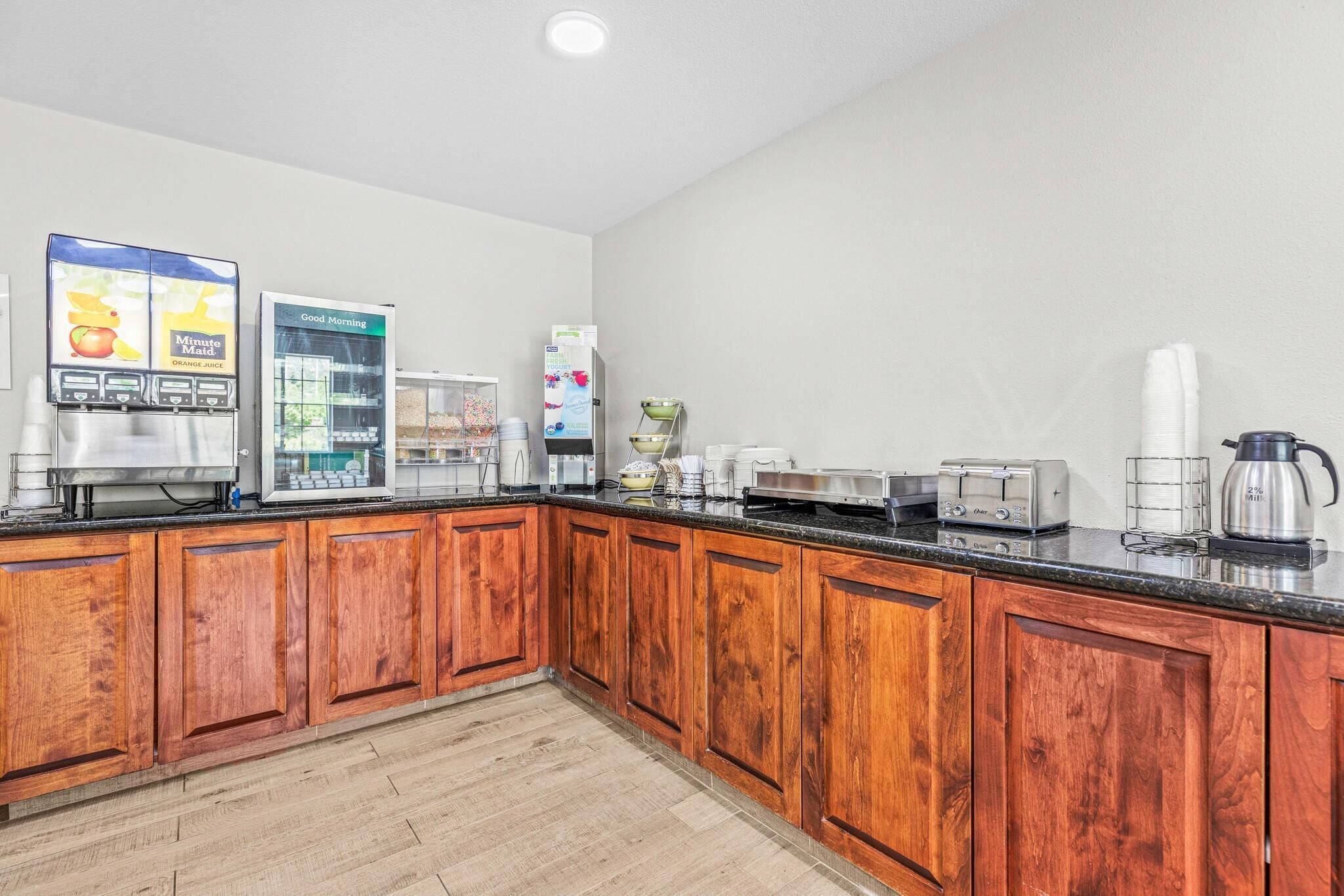 Una cocina con armarios de madera, cafetera, refrigerador, microondas y tostadora.
