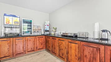 Una cocina con armarios de madera, cafetera, refrigerador, microondas y tostadora.