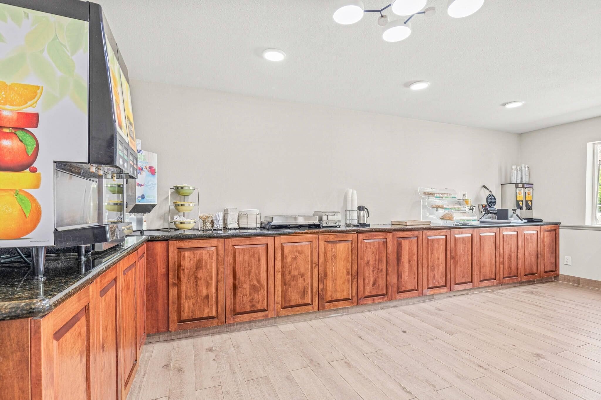 A long wooden counter with various appliances and a large fruit display.