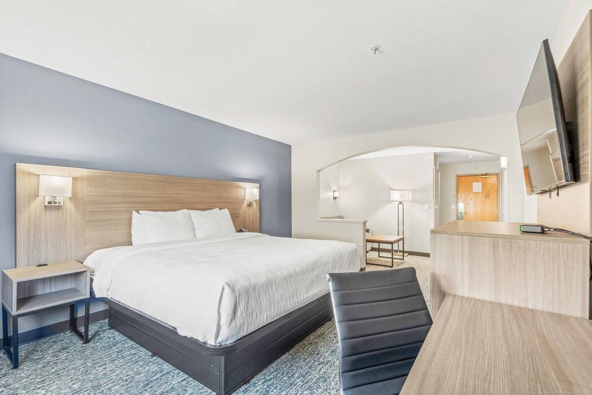 A hotel room with a large bed, bedside tables, a desk, and a chair.