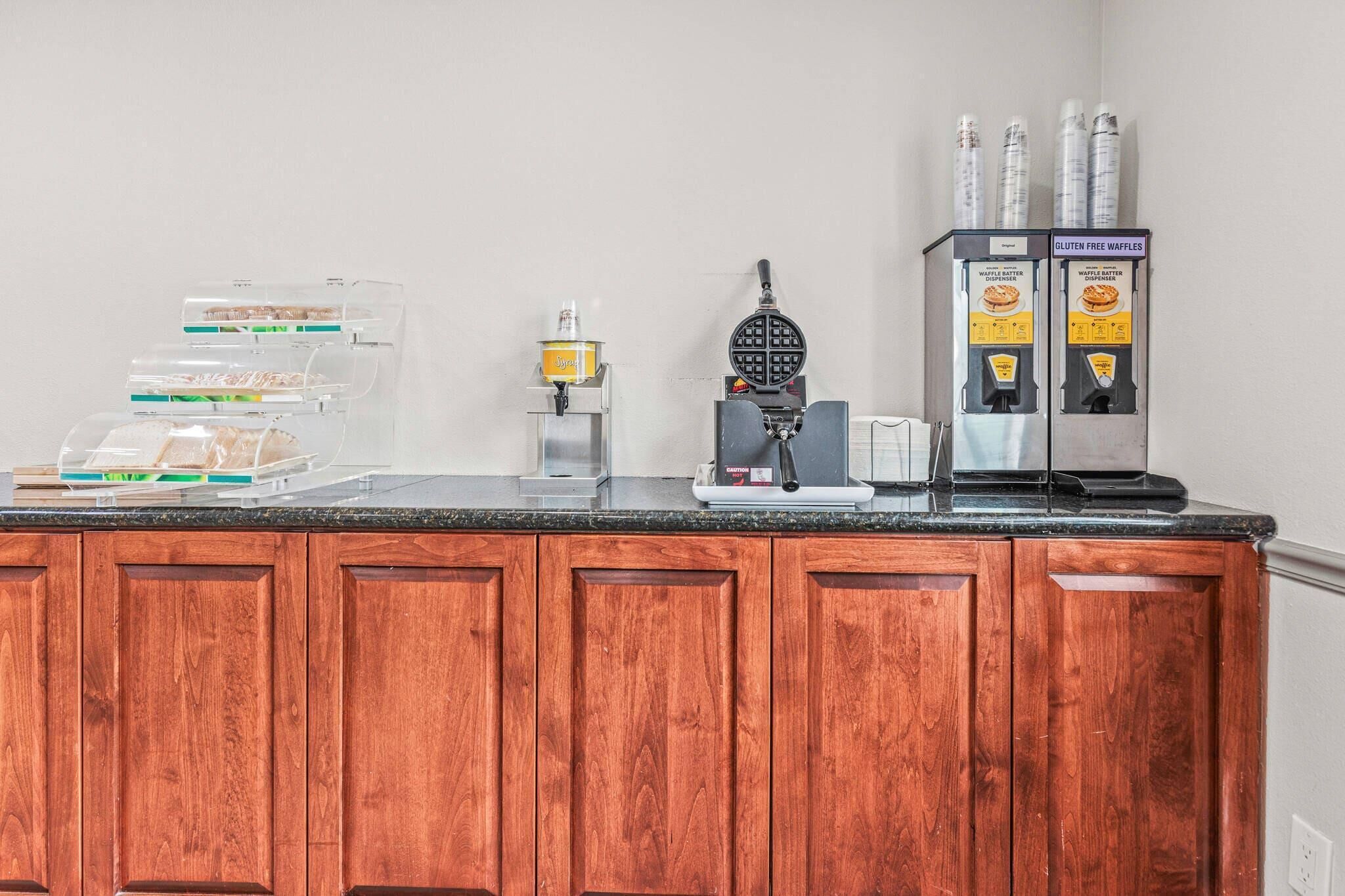 Et tekøkken med vaffeljern, kaffemaskine og en dispenser til glutenfri vafler.
