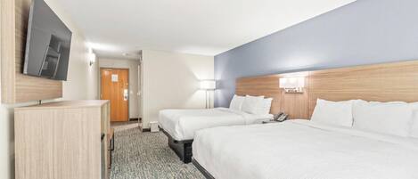 Una habitación de hotel con dos camas, televisión, escritorio y lámpara.