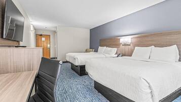Quarto de hotel com duas camas, uma escrivaninha e uma televisão.