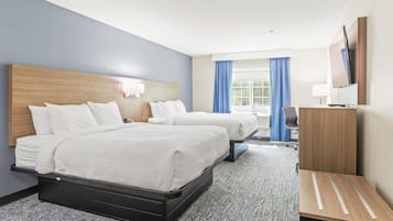 A hotel room with two beds, a desk, a chair, a TV, and a window with curtains.