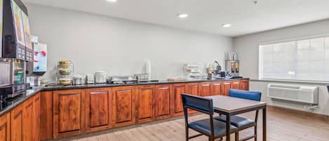 A modern kitchen with wooden cabinets, a central island, and a dining area with a table and chairs.