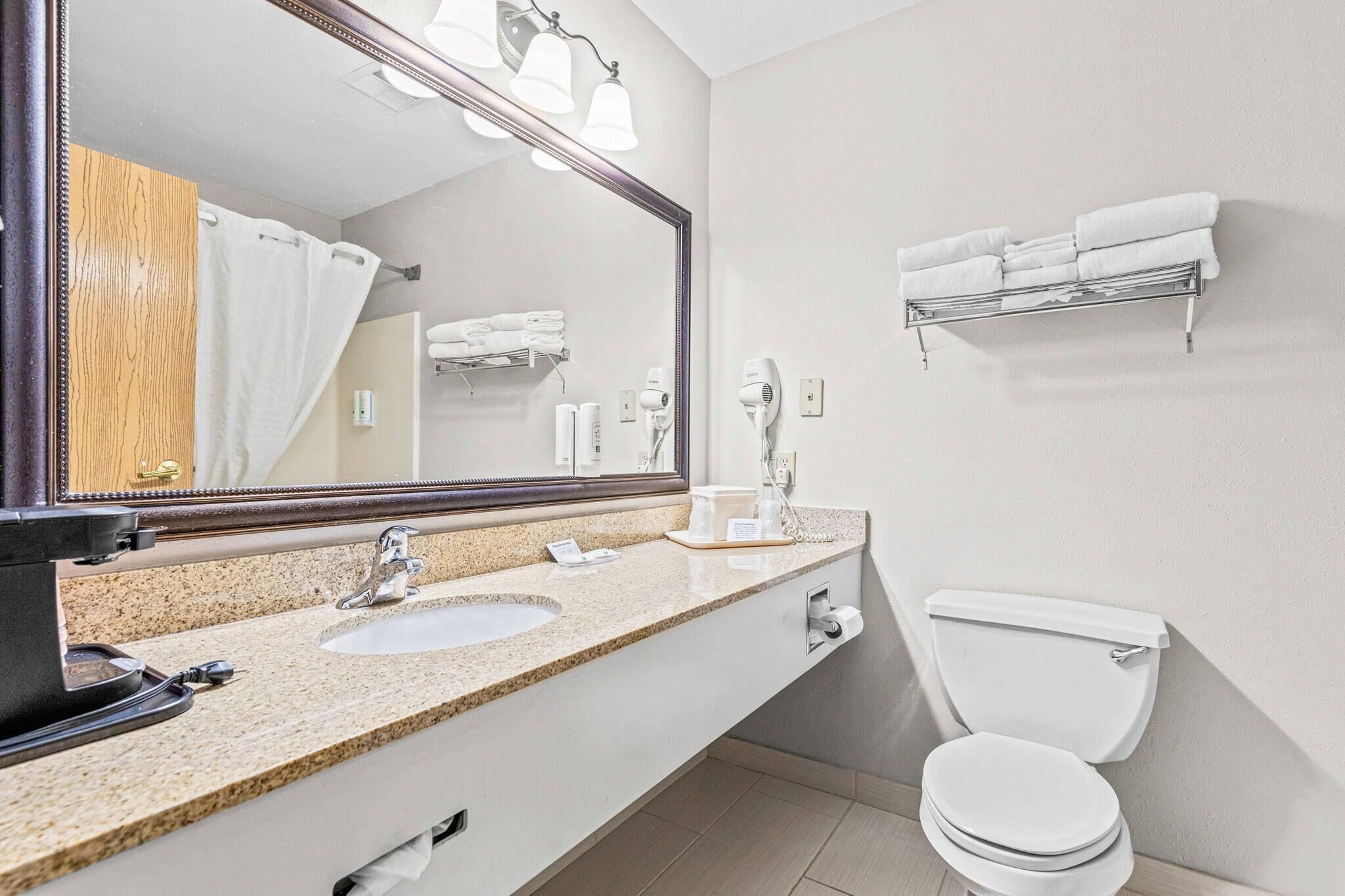 A bathroom with a sink, mirror, towel rack, and toilet.