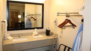 A hotel bathroom with a sink, mirror, towel rack, and a hairdryer. - Highland Inn (Gonzales)
