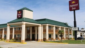 A Highland Inn building with a green roof, multiple balconies, and a sign indicating 'New Room S'. - Highland Inn (Gonzales)