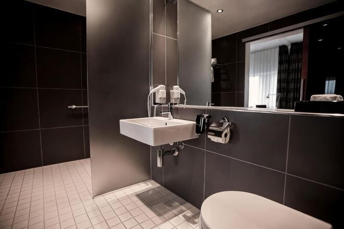 A modern bathroom with a sink, mirror, and toilet.