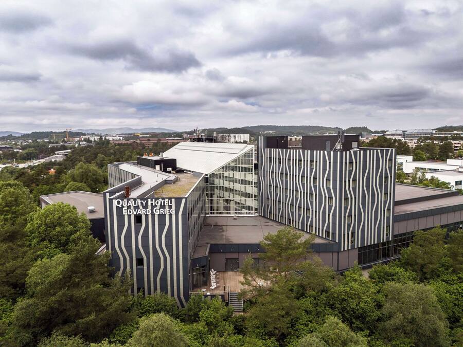 A modern hotel with a distinctive wavy facade, a rooftop garden, and a view of the surrounding cityscape.
