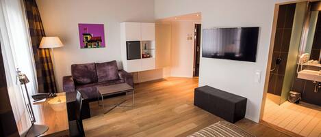 Una sala de estar moderna con un sofá, una mesa de centro, un televisor y un comedor con sillas y una lámpara.