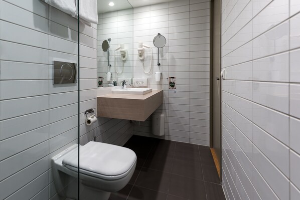 Un baño moderno con inodoro, lavamanos y dos espejos.