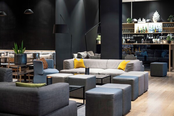 A modern lounge area with sofas, ottomans, and a bar area with shelves and bottles. - Quality Hotel Edvard Grieg (Bergen)