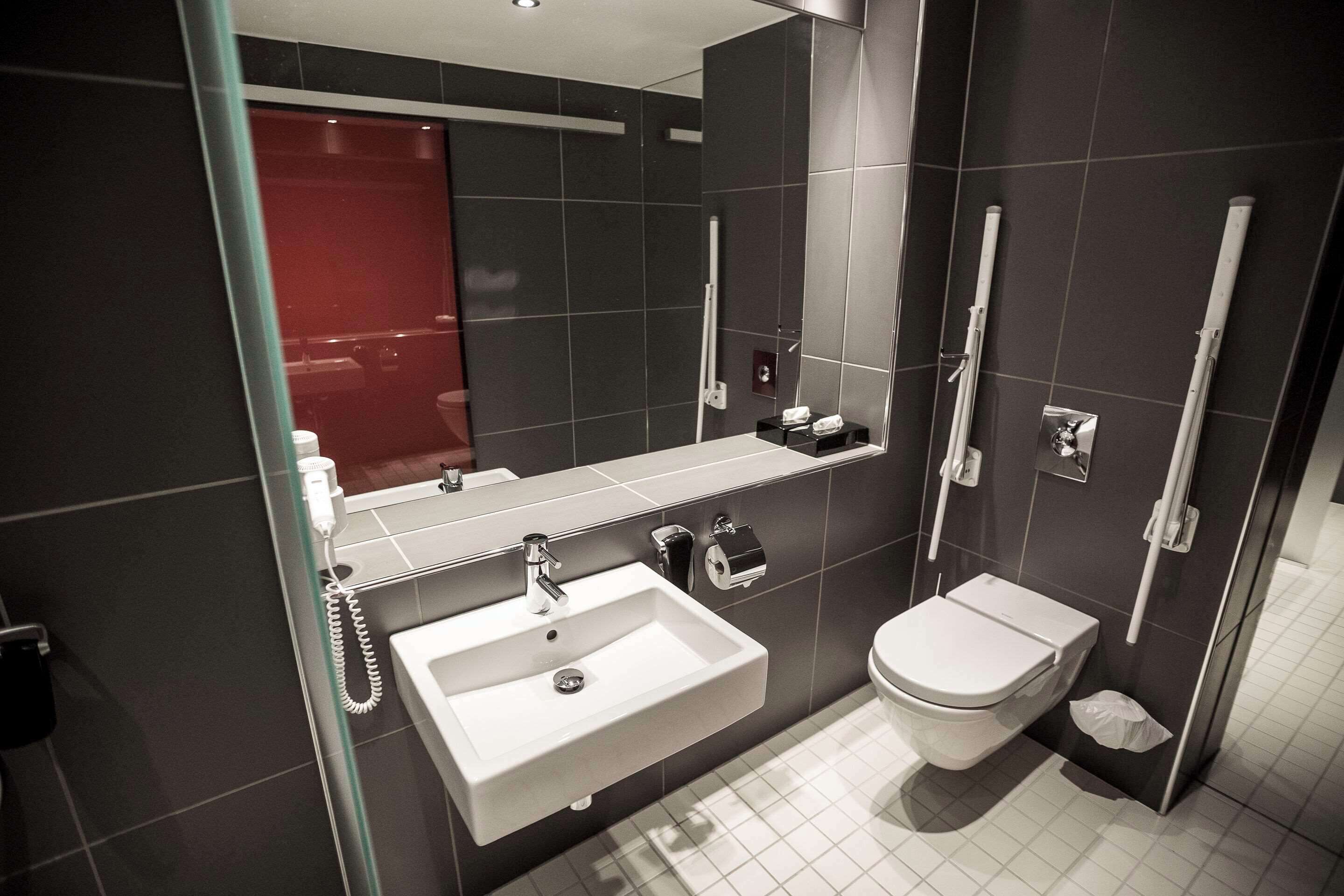 Een moderne badkamer met een wit wastafelmeubel, toilet en een douchecabine met glazen wanden.