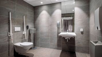 A modern bathroom with a toilet, a sink, and a hand dryer.