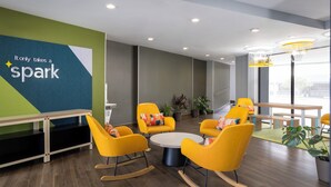 A modern conference room with yellow chairs, a round table, and a green accent wall with the text 'It only takes a spark'. - Spark by Hilton Virginia Beach Oceanfront (Virginia Beach)