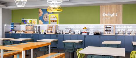 Un café moderne avec des tables et des chaises, un tableau affichant le menu et un mur sur lequel on peut lire : « Savourez chaque instant. »