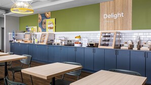 A modern café with blue cabinets, wooden tables, and a green accent wall. - Spark by Hilton Virginia Beach Oceanfront (Virginia Beach)