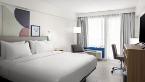 A hotel room with a large bed, a desk, a chair, a lamp, and a window with curtains. - Spark by Hilton Virginia Beach Oceanfront (Virginia Beach)