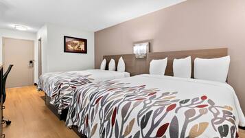 Una habitación de hotel con una cama grande, una mesita de noche, una lámpara de pared y una puerta.