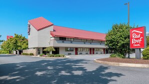 A Red Roof Inn with a red roof, a parking lot, and a clear blue sky. - Red Roof Inn Harrisburg North (Harrisburg)