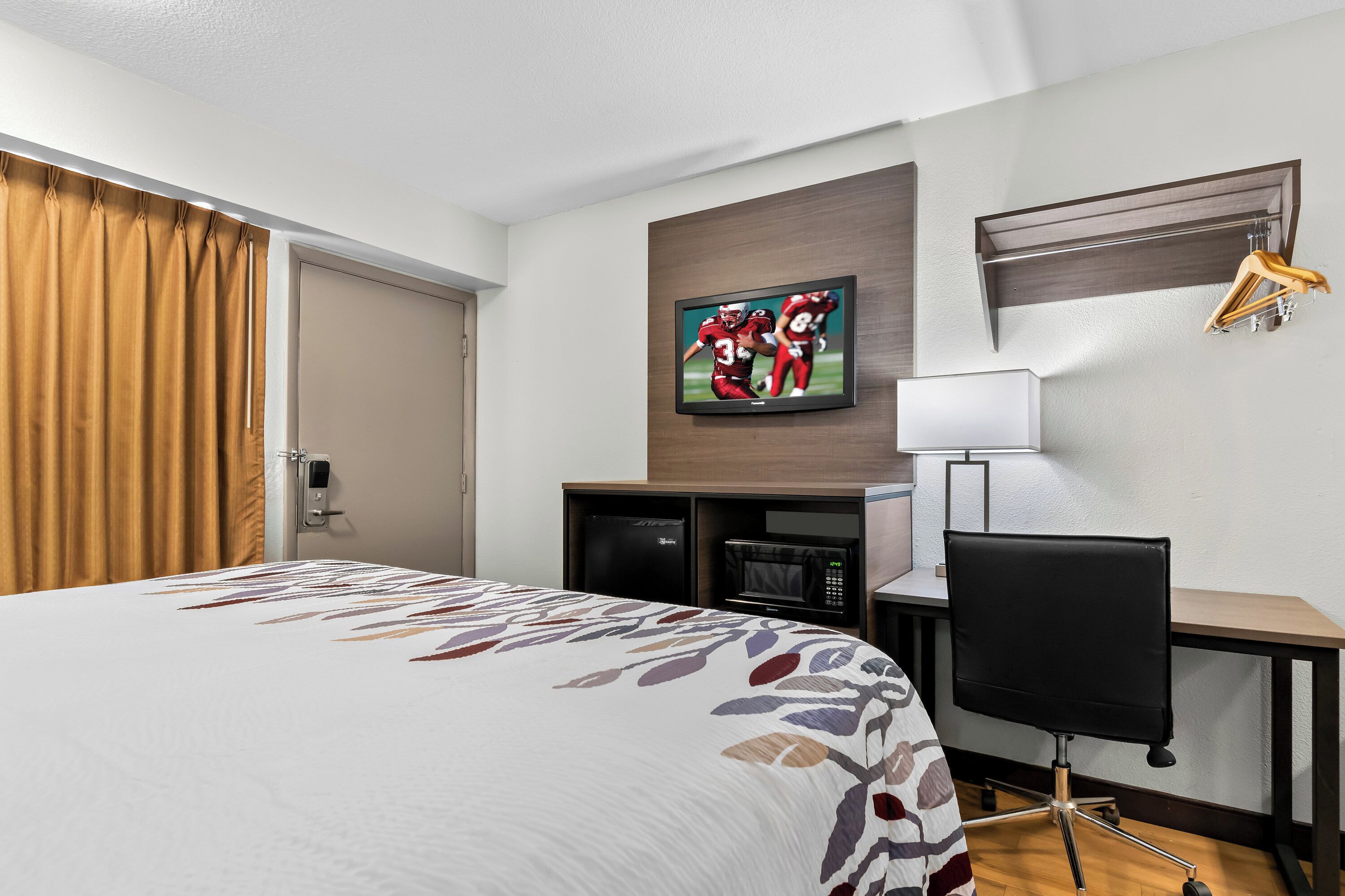 Ein Hotelzimmer mit einem Bett, einem Schreibtisch, einem Fernseher und einem Kleiderschrank.