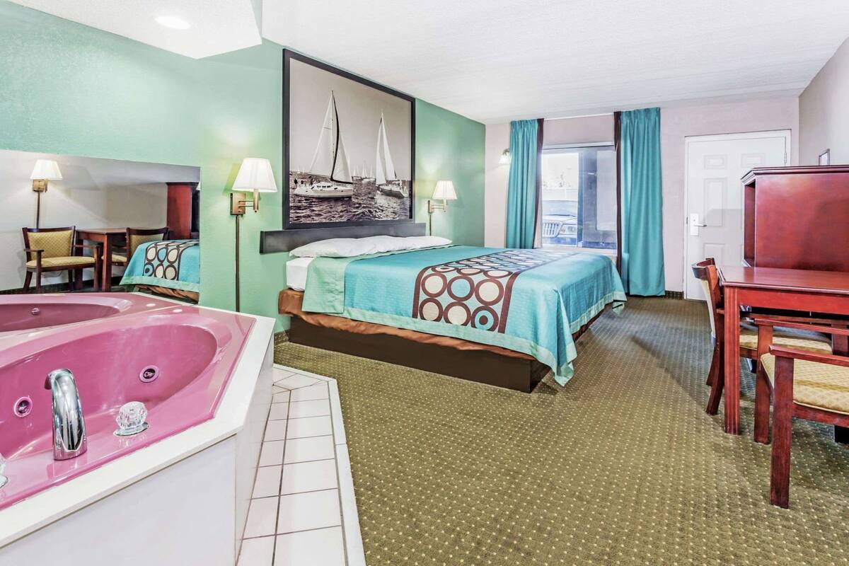 Ein Hotelzimmer mit Bett, Badewanne, Schreibtisch und Stuhl.